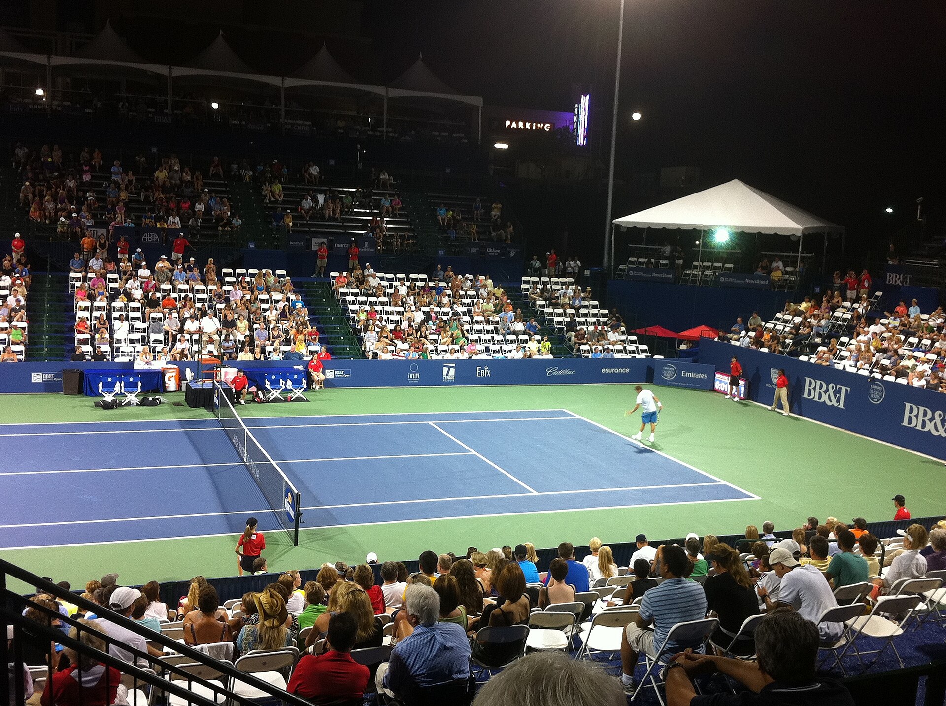 A floodlit ATP hard court during a night session with spectators in the stands